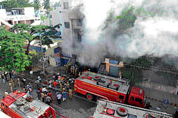 fire fighting: Smoke billows out of a carpet shop that was gutted at Mattikere on  Wednesday. DH Photo