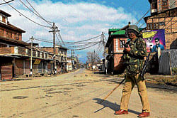 A security person guards a street during curfew in Srinagar on Friday. PTI