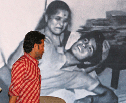 Cricketer Sachin Tendulkar looks at his photograph with his mother during a book launch in Kolkata on Sunday. PTI