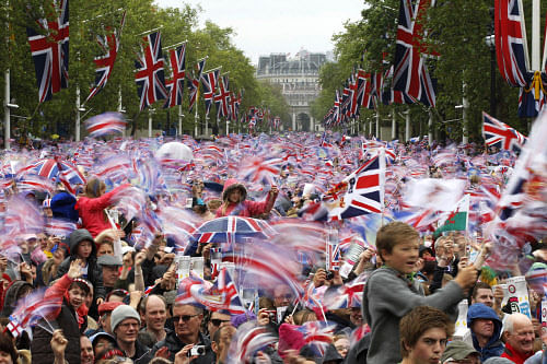 In this June 5, 2012 file photo, revelers on the Mall in London watch Britain Queen Elizabeth II appear on the Buckingham Palace balcony as part of a four-day Diamond Jubilee celebration to mark the 60th anniversary of Queen Elizabeth II accession to the throne. (AP Photo/Sang Tan, File)