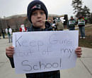 Jack Gilchrist, 10, chews on a candy cane as he holds a 'Keep guns out of my school sign' as he and his mother protest outside the Breslin student center in East Lansing, Michigan December 15, 2012. Union members and supporters were demonstrating against Michigan Governor Rick Snyder, who was the feature speaker at the Michigan State University commencement ceremony, and the 'Right To Work' laws that he had signed on Tuesday. REUTERS