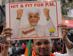 An Indian supporter of the Bhartiya Janta Party (BJP) holds a placard with the photo of Gujarat Chief Minister Narendra Modi during a political rally in Ahmedabad on December 20, 2012. Controversial Hindu nationalist Modi secured a landslide poll victory in the Indian state of Gujarat, firming up his chances of running for prime minister in 2014. AFP