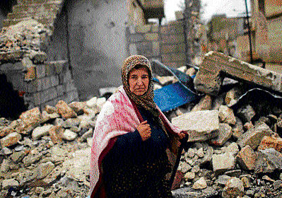 Total destruction: A woman walks past a house destroyed by an airstrike by Syrian government forces according to local residents in Azaz city. REUTERS