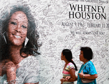 Filipino shoppers walk past the 'tribute wall' for the late American singer Whitney Houston at the SM North EDSA shopping mall in suburban Quezon city, northeast of Manila, Philippines Friday, Feb. 17, 2012. The tribute wall was put up for fans to write their messages following Houston's sudden death Saturday at age 48. AP Photo
