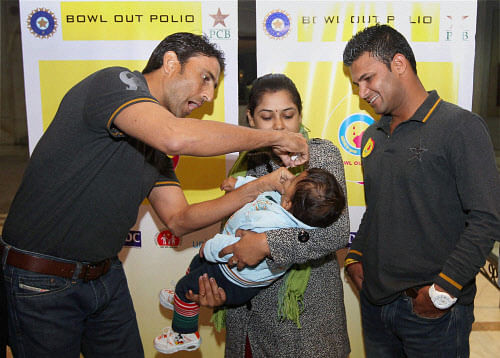 Pakistani cricketers Younis Khan and Imran Farhat giving polio drops to a child at the UNICEF event 'Bowl Out Polio' in New Delhi on Saturday. PTI Photo by