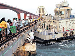 Onlookers gather around a barge that rammed into the century-old Pamban Rail Bridge in Rameshwaram on Sunday. PTI
