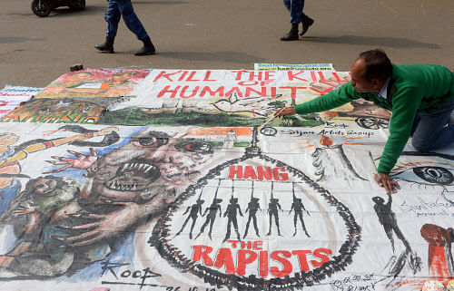 An artists works on a banner calling for the death sentence for rapists during the one-month anniversary of the gang rape and murder of a student in New Delhi on January 16, 2013.