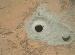 At the center of this image released to Reuters on February 9, 2013 from NASA's Curiosity rover is the hole in a rock called 'John Klein' where the rover conducted its first sample drilling on Mars on February 8, 2013, or Sol 182, Curiosity's 182nd Martian day of operations. The image was obtained by Curiosity's Mars Hand Lens Imager (MAHLI) on Sol 182. The sample-collection hole is 0.63 inch (1.6 centimeters) in diameter and 2.5 inches (6.4 centimeters) deep. The 'mini drill' test hole near it is the same diameter, with a depth of 0.8 inch (2 centimeters). REUTERS
