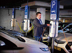 Fledgling market: Patrick Langevoort charges his electric car at his workplace in Arnhem, Netherlands. NYT