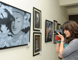 Yong Girl taking a photograph of paintings at the Karnataka Chitrakala Parishath . DH photo