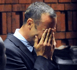 South Africa's Olympic sprinter Oscar Pistorius (R) hides his face in his hands in the court room during his hearing on charge of murdering his model girlfriend Reeva Steenkamp on Valentine's Day on February 15, 2013 at the Magistrate Court in Pretoria. South African prosecutors will argue that Pistorius is guilty of premeditated murder in Steenkamp's death, a charge which could carry a life sentence. AFP PHOTO/