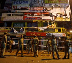 Policemen guard a shopping arcade, damaged in one of the two bomb blasts, in Hyderabad, India, early Friday, Feb. 22, 2013. A pair of bombs exploded Thursday evening in a crowded shopping area in the southern Indian city of Hyderabad, killing at least 12 people and wounding scores of others in the worst bombing in the country in more than a year, officials said. (AP Photo