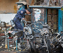 An official of India's National Investigation Agency looks for evidence in the debris at one of the two bomb blast sites, in Hyderabad, India, Friday, Feb. 22, 2013. A day after two bicycle bombs killed more than a dozen people and wounded more than 100, investigators into India's worst bombing in more than a year searched Friday for possible links to anger over the execution of a Muslim militant. (AP Photo/