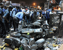 Indian police and investigators are pictured at the site of a bomb blast at Dilshuk Nagar in Hyderabad on February 21, 2013. At least 18 people were killed and 52 wounded when bombs ripped through crowded areas of the Indian city of Hyderabad on Thursday in what the prime minister called a 'dastardly act'. AFP PHOTO