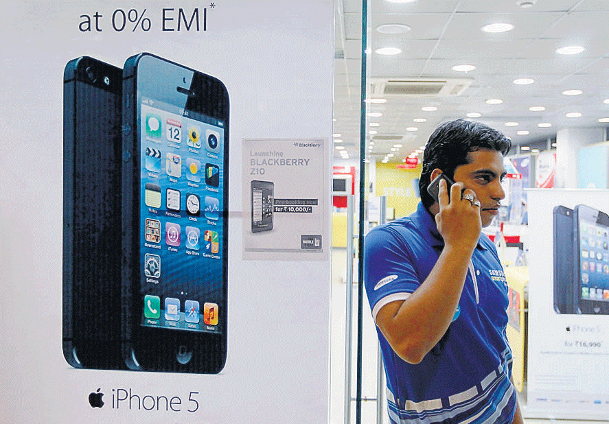 A man speaks on his mobile phone next to a poster advertising an Apple iPhone 5 in Ahmedabad. Reuters