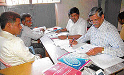 Election officer Kadiregowda and assistant election officer Shivalingaiah scrutinise the  nominations in Kolar on Monday. dh photo