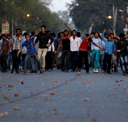Protesters hurl stones towards police officers during a protest against the rape of a 7-year-old girl in New Delhi, India, Friday, March 1, 2013. Police are investigating the rape inside a state-run school in the Indian capital. Angry mobs gathered at the hospital and threw stones at a nearby bus, shattering its windows. Police cordoned off the road and were trying to disperse the crowd. (AP Photo