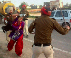 Tarn Taran: Police personnel charging a woman after she along with her father tried to lodge a complaint against her molestation by some truck drivers in Tarn Taran on Monday. PTI Photo