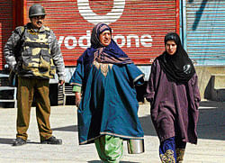 A paramilitary trooper keeps watch as Kashmiri women walk past during a curfew in downtown Srinagar on Wednesday.  AFP
