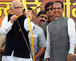 Senior BJP leader LK Advani aims with an arrow and bow at the launch of Madhya Pradesh government's 'Atal Jyoti Abhiyan', 24-hr electricity supply, in Shahdol district on Saturday. MP Chief Minister Shivraj Singh Chouhan (R) is also seen. PTI Photo