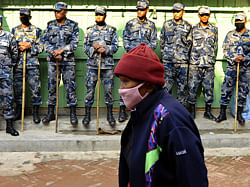 A Tibetan Buddhist woman prays as she walks around the Bouddhanath Stupa as Nepalese security force personnel stand guard during the 54th anniversary of the 1959 Tibetan uprising against Chinese rule, in Kathmandu on March 10, 2013. Nepalese police arrested 11 people in Kathmandu on suspicion of 'anti-China activities' on Sunday morning, the anniversary of the 1959 rebellion against China's rule in Tibet. AFP PHOTO