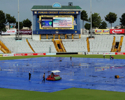 Groundmen clear the pitch for the 3rd Test between India and Australia as rain delayed the match at PCA Stadium in Mohali on Thursday. PTI Photo