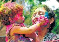 RIOT OF COLOURS:A child smears colours on her mother, on the eve of holi at Vijayanagar in the City on Tuesday . DH PHOTO