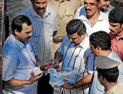 Members of the bomb detection and disposal squad inspect the materials found in the gift box placed outside J B Suranas house at Indiranagar on Thursday. DH Photo