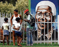 Visitors gather in front of a portrait of former president  Nelson Mandela in a Park in Soweto, South Africa, on  Thursday. ap
