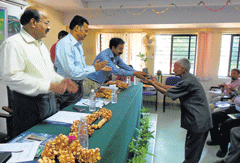 Forest College dean Dr N A Prakash hands over bamboo sapling to a Bamboo grower Ponnappa, at a seminar on                        bamboo cultivation held at Ponnampet Forest College  in Gonikoppa. DH Photo