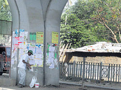 A worker pasting fliers under the Agara Flyover.