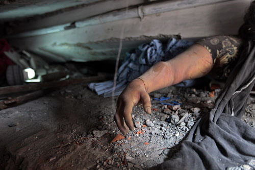 A victim's body is trapped in rubble after an eight-story building housing several garment factories collapsed in Savar, near Dhaka, Bangladesh, Wednesday, April 24, 2013. AP
