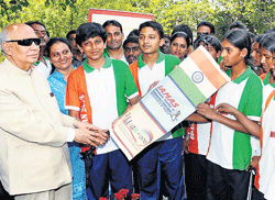 Governor H R Bhardwaj, on Wednesday, hands over the Tricolour to tribal students who  will go on an expedition to the Himalayas. DH Photo