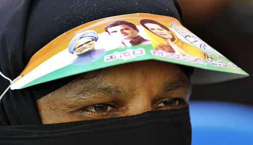 A veiled Muslim woman sports a sun-shade featuring portraits of Congress party leaders, Prime Minister Manmohan Singh, left, Rahul Gandhi, center, and Sonia Gandhi during a campaign rally for the upcoming state elections, attended by Rahul Gandhi in Tumkur, 70 Kilometers (43 miles) northwest of Bangalore, India, Friday, April 26, 2013. The southern Indian state of Karnataka will go to the polls on May 5, 2013. There are 41.8 million voters in the state and as many as 50,446 polling stations will be set up ahead of the polls, election commission said. (AP Photo/Aijaz Rahi)