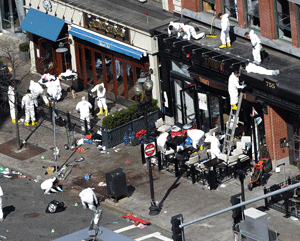 In this Wednesday, April 17, 2013 file photo, investigators comb through the scene of one of the blast sites of the Boston Marathon explosions in Boston. Three more suspects were taken into custody in the Boston Marathon bombing case, including two college friends of Dzhokhar Tsarnaev who came to the U.S. from Kazakhstan, officials said Wednesday May 1, 2013. (AP Photo