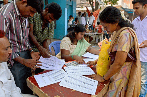 Voters check their names on a voters list near a polling booth during state Assembly elections in Bangalore on May 5, 2013. AFP photo