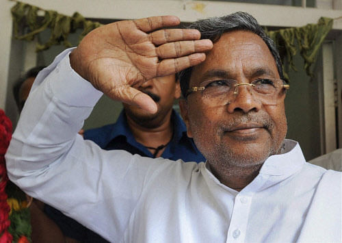 Congress leader & Chief Minister aspirant Siddaramaiah gestures at his supporters outside his residence in Bengaluru on Thursday. PTI Photo