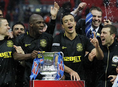 Wigan Athletic players celerbate with the FA Cup after winning the English FA Cup final football match between Manchester City and Wigan Athletic at Wembley Stadium in London on May 11, 2013. AFP PHOTO