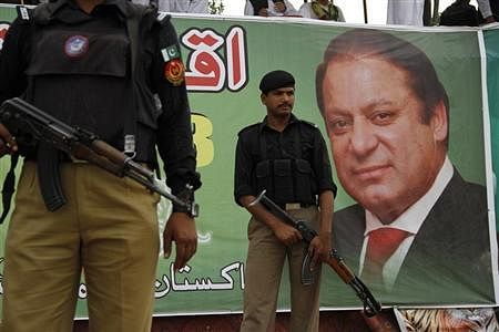Policemen guard near the portrait of Nawaz Sharif, leader of political party Pakistan Muslim League-Nawaz (PML-N), during an election campaign rally in Peshawar May 7, 2013.  Credit: Reuters