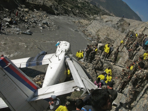 Nepalese onlookers and rescuers stand near the wreckage of the Nepal Airlines Twin Otter aircraft crash site in Jomsom, some 300 kms west of Kathmandu, on May 16, 2013. Twenty-one people were hurt, including eight Japanese tourists, when a small plane skidded off a Nepal airport runway and plunged into a river, police said. All 21 people aboard the Nepal Airlines Twin Otter aircraft were injured, five seriously, police spokesman Keshav Adhikari said. AFP PHOTO