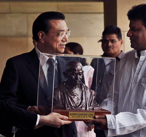 Chinese Premier Li Keqiang, center, receives the bust of Mahatma Gandhi at the Mahatama Gandhi memorial in New Delhi, India, Monday, May 20, 2013. Just weeks after a tense border standoff, China's new premier visited India on Sunday on his first foreign three-day trip as the neighboring giants look to speed up efforts to settle a decades-old boundary dispute and boost economic ties. (AP Photo