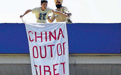 A policeman (R) detains a Tibetan youth activist who unfurled a banner from atop a fuel station near the Taj Hotel where the visiting Chinese premier Li Keqiang is staying in New Delhi on Monday. AP
