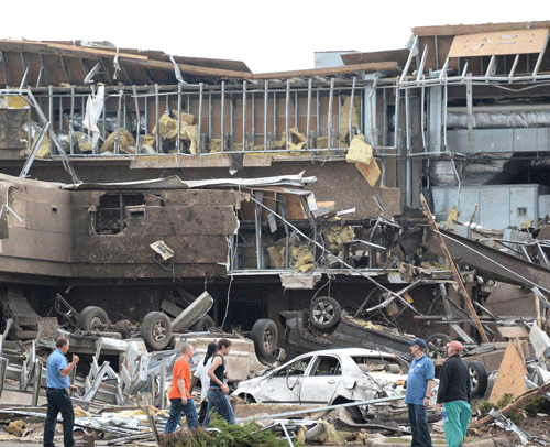 People survey the destructions at the Moore hospital after it was hit by a tornado that destroyed buildings and overturned cars in Moore, Oklahoma, May 20, 2013. A huge tornado with winds of up to 200 miles per hour (320 kph) devastated the Oklahoma City suburb of Moore on Monday, ripping up at least two elementary schools and a hospital and leaving a wake of tangled wreckage. REUTERS