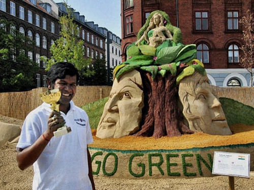 Sand artist Sudarsan Pattnaik showing his Danish grand prize which he has won in 2nd Copenhagen International Sand Sculpture Festival 2013 for his sand sculpture on Go green, Save Earth, at Copenhagen on Monday. PTI Photo