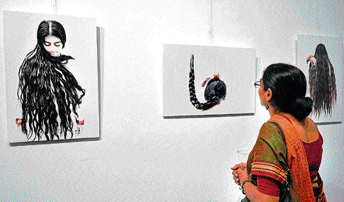 Feminine Art: A woman looks at the photograph of women with braided hair.
