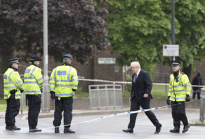 Mayor of London Boris Johnson (2-R) arrives at a police cordon in Woolwich, London on May 23, 2013, at the site of the murder of a soldier by two suspected Islamists. Prime Minister David Cameron vowed that Britain would be resolute against violent extremism following the gruesome murder of a soldier by two suspected Islamists on a London street. After chairing a meeting of security chiefs the day after the soldier was hacked to death in broad daylight, he said Britain's communities would unite in condemning an attack he described as a 'betrayal of Islam'. AFP PHOTO / JUSTIN TALLIS