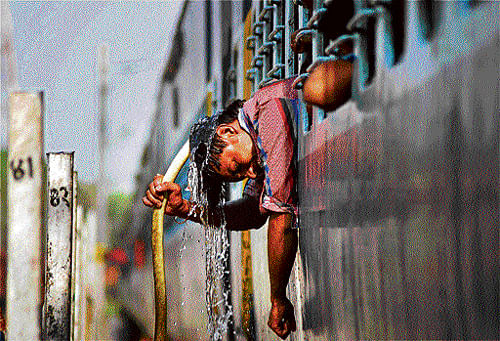 Beating heat: A passenger pours water over his head to cool off the scorching heat at Allahabad railway station on Saturday.  PTI