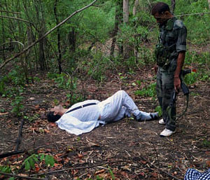 An Indian security person stands near the body of one of the victims of Saturday's Maoist attack in a densely forested area in Bastar, about 345 kilometers (215 miles) south of Raipur, Chhattisgarh state, India, Sunday, May 26, 2013. Officials reacted with outrage Sunday to an audacious attack by about 200 suspected Maoist rebels who set off a roadside bomb and opened fire on a convoy carrying Indian ruling Congress party leaders and members in an eastern state, killing at least 24 people and wounding 37 others. (AP Photo)