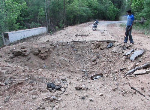 An unidentified man stands near the crater created on the road after Saturday's Maoist land mine attack in a densely forested area in Bastar, about 345 kilometers (215 miles) south of Raipur, Chhattisgarh state, India, Sunday, May 26, 2013. Officials reacted with outrage Sunday to an audacious attack by about 200 suspected Maoist rebels who set off a roadside bomb and opened fire on a convoy carrying Indian ruling Congress party leaders and members in an eastern state, killing at least 24 people and wounding 37 others. (AP Photo