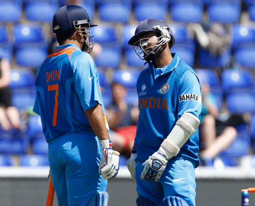 MS Dhoni, left, chats with Dinesh Karthik, right, to congratulate him on scoring 50 runs during a warm up cricket match for the upcoming ICC Champions Trophy between India and Australia at the Cardiff Wales Stadium in Cardiff, Wales, Tuesday, June 4, 2013. (AP Photo)